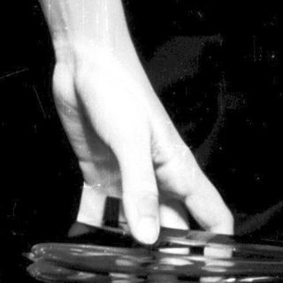 Here's a brief summary of the image: Hand holds a shattered glass, dark background.