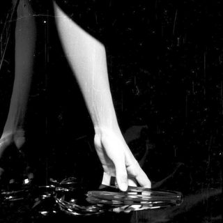 Here's a brief summary of the image: Hand holds a shattered glass, dark background.