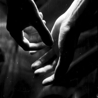 Hands forming a heart shape against a blurred background.