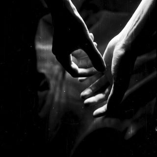 Hands forming a heart shape against a blurred background.