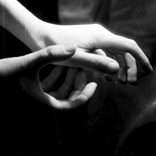 Two hands reach toward each other in darkness.