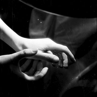 Two hands reach toward each other in darkness.