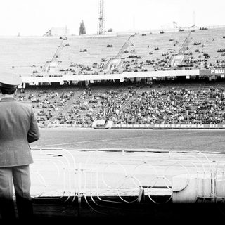 Men overlook a stadium filled with a large crowd.