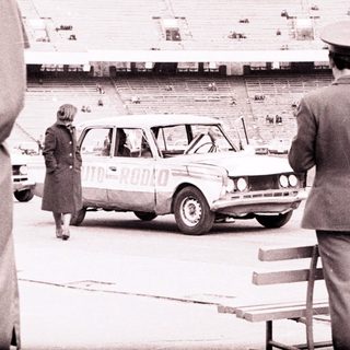 Officials observe a car near an empty stadium.