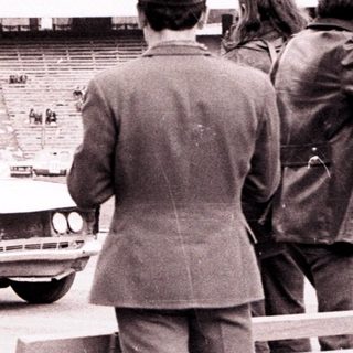 Officials observe a car near an empty stadium.