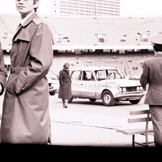 Officials observe a car near an empty stadium.