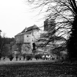 Black and white photo of a castle on a rocky hillside.