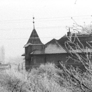 Snow-covered landscape with trees, houses, and a church steeple.