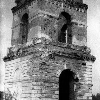 Ruined brick tower with arches, overgrown with vegetation.
