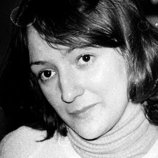 Here's a brief summary of the image: Woman in turtleneck sweater, looking at the camera.