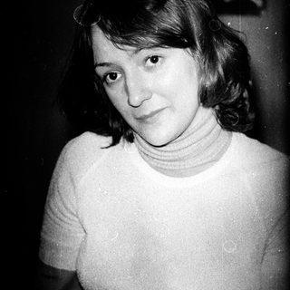 Here's a brief summary of the image: Woman in turtleneck sweater, looking at the camera.