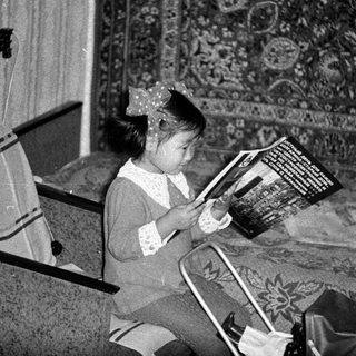 Girl sits reading a book in a vintage room.