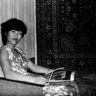 Woman seated, reading a magazine in a vintage room.