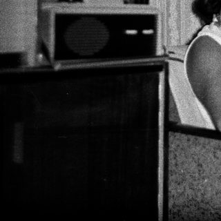 Woman seated, reading in a room with vintage furnishings.