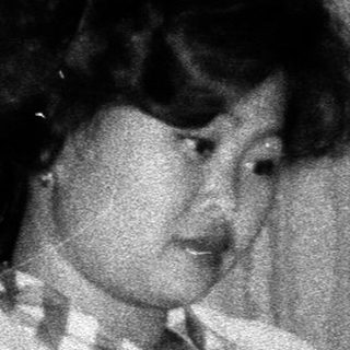 Woman seated, reading in a room with vintage furnishings.