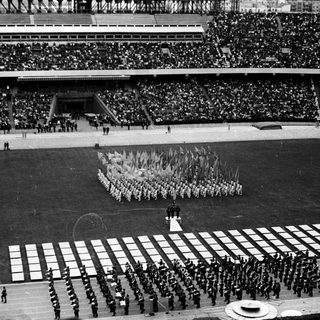 Large group arranged in formation on a stadium field.