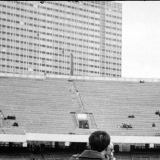 Photographers capture an athlete jumping in a stadium.