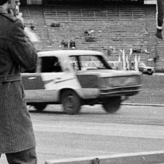 Photographers capture an athlete jumping in a stadium.