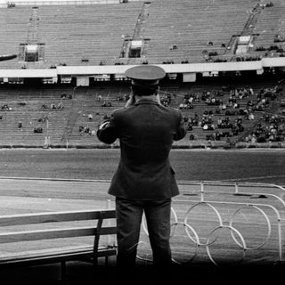 Photographers capture an athlete jumping in a stadium.