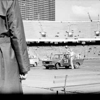Man performing a stunt involving a car in a stadium.