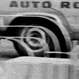 Truck at an auto rodeo event with a blurred stadium backdrop.