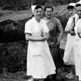 Nurses stand near a trench, possibly during wartime.