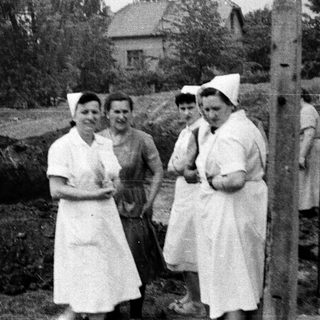 Nurses stand near a trench, possibly during wartime.