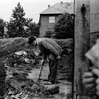 Man with cane looks down on a slope.