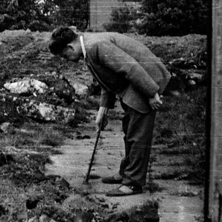 Man with cane looks down on a slope.
