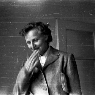 A person in vintage clothing resting chin on hands.