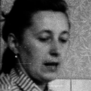 Woman brushing teeth in tiled bathroom.
