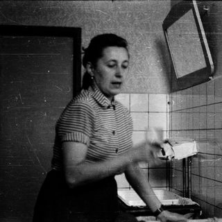 Woman brushing teeth in tiled bathroom.