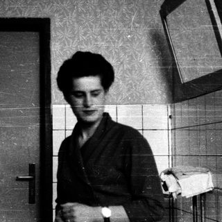Young man in traditional attire standing in a tiled bathroom.