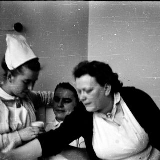 Two nurses attending to a patient in a medical setting.