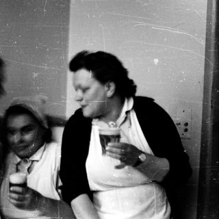 Nurses in 1940s-50s uniforms drinking together indoors.