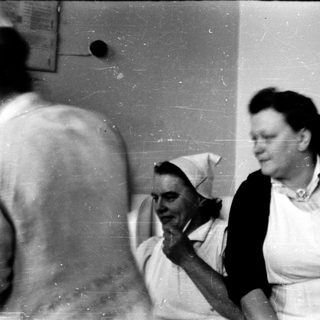 Two women in nursing uniforms appear engaged indoors.
