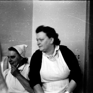Two women in nursing uniforms appear engaged indoors.