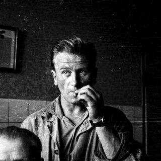 Men in dimly lit room, smoking cigarettes.