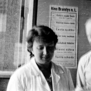 Two people standing indoors near a cinema poster.
