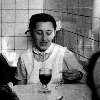 Nurse enjoying meal with wine indoors.