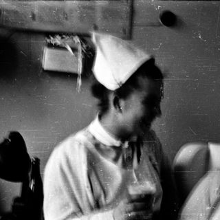 Nurses in traditional caps smiling indoors.