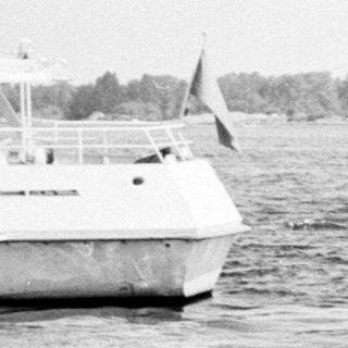 Two people launching small motorboat into water.