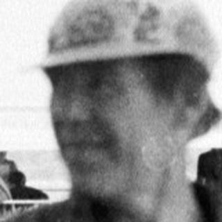 Old man in military cap by waterfront.