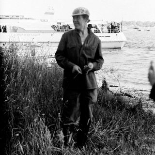 Old man in military cap by waterfront.