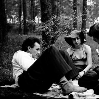 Four people sitting outdoors in a forest setting.
