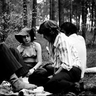 Four people sitting outdoors in a forest setting.