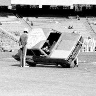 Empty stadium with construction vehicles, security personnel, and tents.