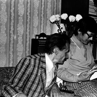 Two men reading books indoors together.