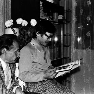 Two men reading books indoors together.