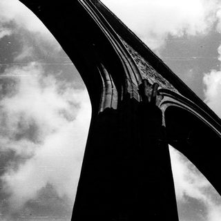 Curved bridge structure against cloudy sky.